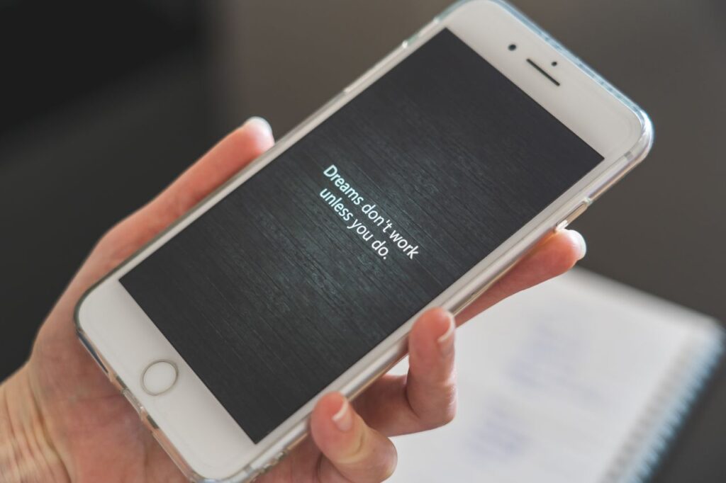 Crafting Captivating Headlines: Your awesome post title goes here Close-up of hand holding smartphone with motivational quote 'Dreams don't work unless you do.'