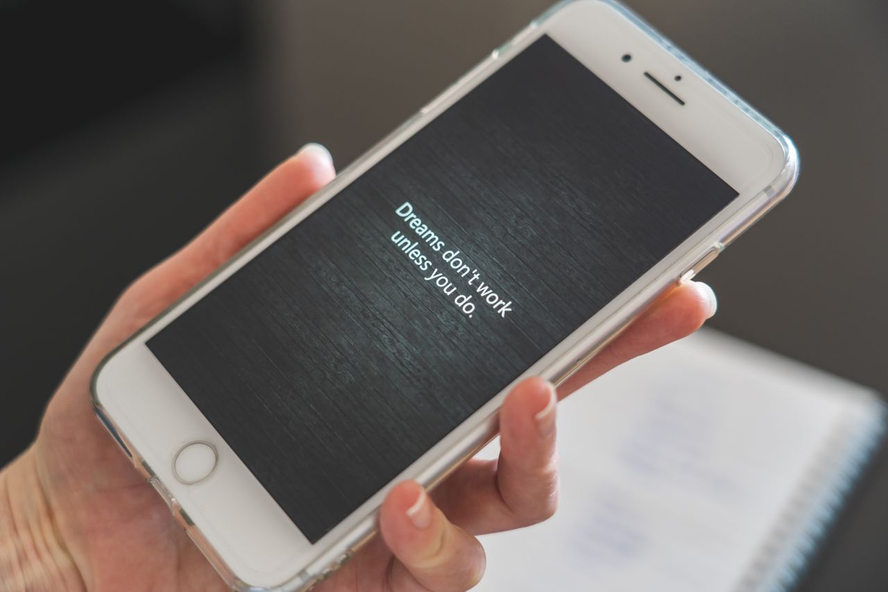 Crafting Captivating Headlines: Your awesome post title goes here Close-up of hand holding smartphone with motivational quote 'Dreams don't work unless you do.'